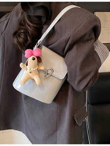 Sac seau bleu clair chic avec fermoir argenté et breloque chien porté à l'épaule
