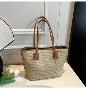 Détail du sac cabas en paille d'été avec bordure en cuir marron et poignées nouées