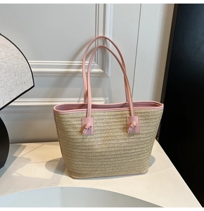 Détail d'un sac en paille tressée avec anses en cuir rose et finitions nouées