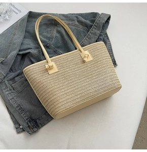 Détail du sac cabas en paille tissée avec poignée en cuir nouée sur une veste en jean