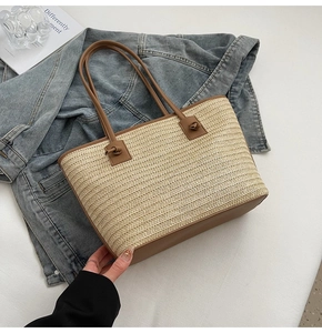 Détail d'un cabas en paille avec anses en cuir marron et nœuds sur fond de denim bleu