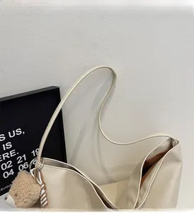 Close-up of cream leather tote bag featuring a plush bear charm and fine texture details