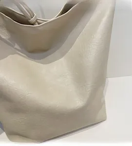 Detail of soft cream faux leather texture and premium stitching on minimalist tote bag