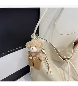 Detail of light brown plush bear charm with corduroy overalls on a white tote bag