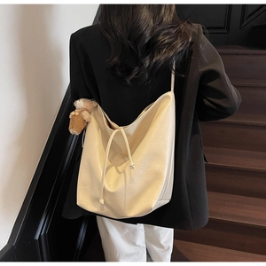 Detalle del bolso tote de cuero sintético crema con colgante de oso y estilo de cordón