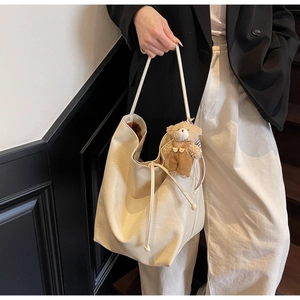 Detalle del bolso tote blanco crema en piel sintética con un colgante de oso de peluche