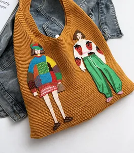 Detail of yellow knitted tote bag featuring stylish colorful character embroidery