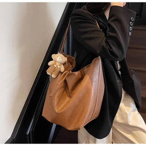 Detalle de bolso tote vintage de cuero marrón con cordón y colgante de osito