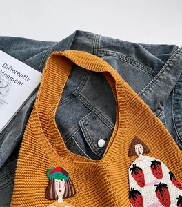 Detail of ginger yellow knitted tote bag with waffle texture and cartoon girl embroidery