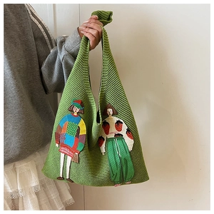 Detail der grünen Stricktasche mit bunten Stickmustern von Comic-Mädchen für Frauen