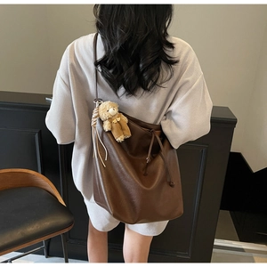 Primer plano de bolso tote de piel sintética marrón con un colgante de osito de peluche