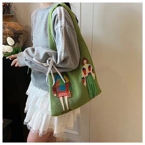 Detail der grünen Strick-Tote-Bag mit künstlerischer Cartoon-Mädchen-Stickerei