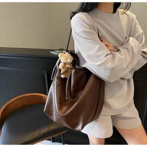 Detail of a dark brown vintage tote bag with drawstring closure and plush bear charm