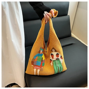 Detail der senfgelben Strick-Tasche mit dicker Wolltextur und Cartoon-Mädchen-Stickerei