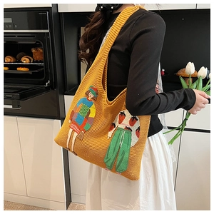 Details der gelben Stricktasche mit bunten Cartoon-Aufnähern und grober Strickstruktur