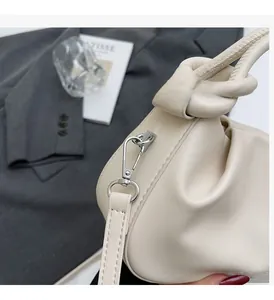 Detail shot of pleated cream cloud bag featuring silver hardware and knotted handle strap