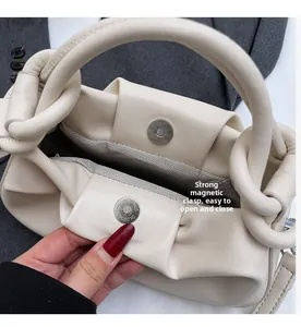 Detail view of cream handbag featuring secure dual magnetic closures and herringbone lining