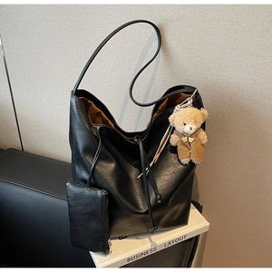 Detail of black leather tote bag with caramel lining and cute teddy bear charm accessory