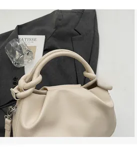 Detail of cream pleated cloud bag featuring knotted handle and detachable shoulder strap