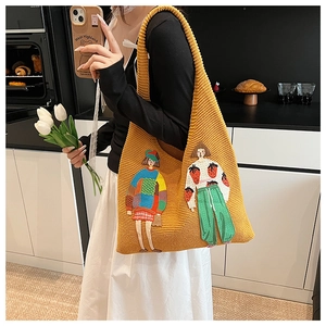 Detail der Textur einer gelben Stricktasche mit kunstvoller Mädchen-Stickerei