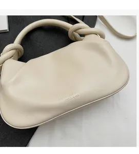 Close-up of the elegant knotted handle and cream leather texture of the handbag