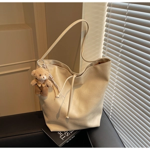 Detail of beige large tote bag with lychee grain texture and cute plush bear charm