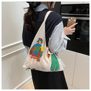 Detail einer cremefarbenen Stricktasche mit lebhafter Stickerei im modernen Stil