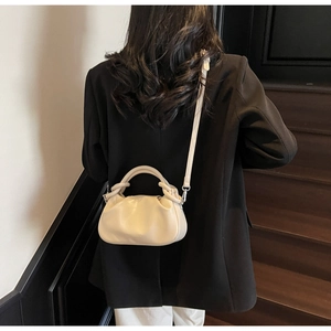 Close-up of ruched cloud handbag with knotted handle on a black blazer model