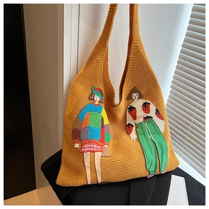 Detailansicht der gelben Stricktasche mit bunter Cartoon-Mädchen-Stickerei