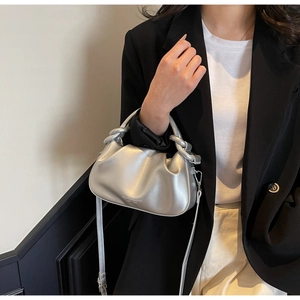 Detail of silver pleated cloud bag featuring metal ring handle and brand logo print