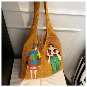 Detail einer ingwergelben Stricktasche mit künstlerischer Stickerei von Comic-Mädchen