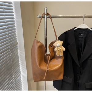 Detalle de bolso tote de cuero sintético marrón con cordón y un colgante de osito