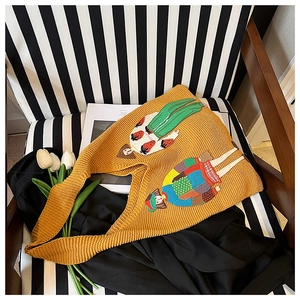 Detailansicht der gelben Stricktasche mit Modeillustration auf einem Streifenstuhl