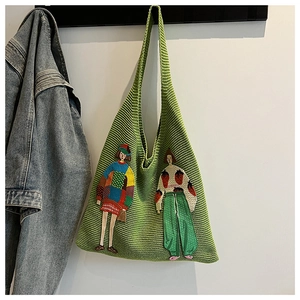 Detail einer grünen Stricktasche mit modischer Cartoon-Stickerei an einem Kleiderbügel