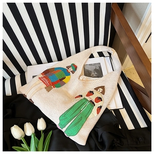 Detail einer beigen Stricktasche mit bunter Cartoon-Stickerei und dicker Garnstruktur