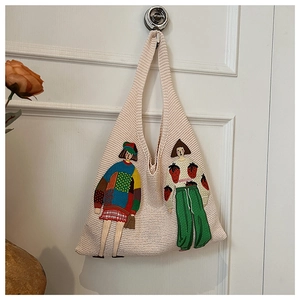 Detail einer Strick-Tote-Bag mit kunstvollen Stickereien und cremeweißer Textur