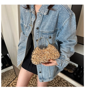 Detailed close-up of golden sequin evening clutch bag with round metal ring handle