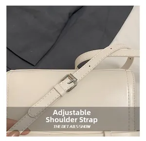 Detail shot of the adjustable shoulder strap with silver buckle on off-white leather bag