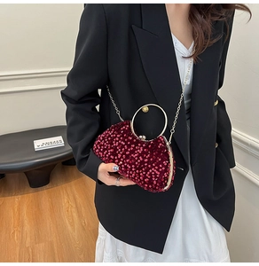 Detail of burgundy sequin evening bag with gold ring handle and metallic chain strap
