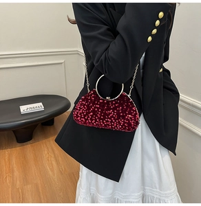 Close-up of red sequin evening bag featuring gold round metal handle and chain strap