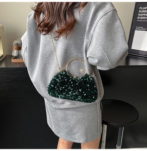 Detail of dark green sequin evening bag with gold metal handle and chain strap