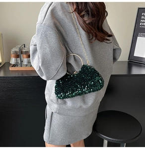 Close-up of sparkling dark green sequin clutch bag with golden ring handle and chain