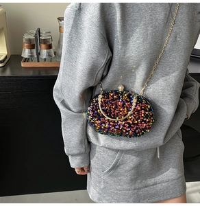 Close-up of sparkling sequin evening bag with gold chain strap and metal handle