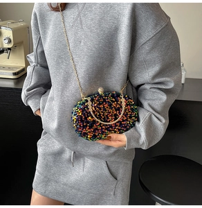 Detailed shot of an oval sequined clutch bag featuring a gold metal handle and chain strap