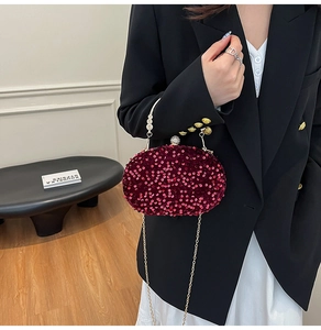 Macro detail of burgundy sequin evening bag with gold chain and metal handle