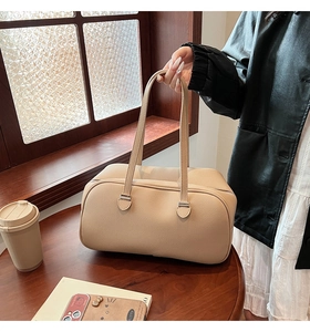 Close-up of beige lychee grain leather handbag with fine stitching and dual handles