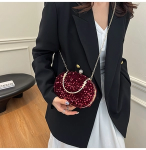 Detail of burgundy sequin evening clutch with golden metal handle and crystal clasp