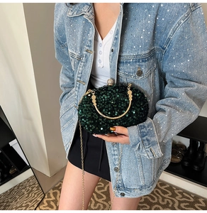 Detailed view of dark green sequin evening clutch with golden metal handle and chain