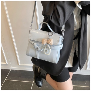Light blue faux leather handbag with pearl bow charm worn with a black blazer