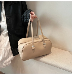 Close-up of beige leather pillow bag with lychee texture and silver metal buckles